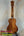 Wooden ukulele with decorative headstock on stand, showcasing KoAloha KCM-00 Concert design