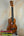 Wooden ukulele with natural finish on stand; KoAloha KCM-00 Concert, Solid Hawaiian Koa