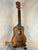 Wooden KoAloha KCM-10 Concert Ukulele in Solid Hawaiian Koa resting on a stand