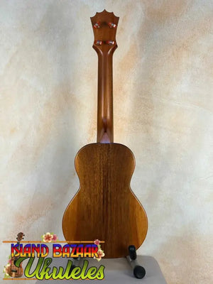 Wooden KoAloha KCM-10 Concert Ukulele in Solid Hawaiian Koa on black display stand