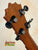 Guitar headstock with black tuning pegs and brown wood grain for KoAloha KSM-00 Soprano Ukulele