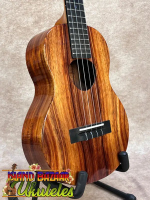 A koaloha ktm-00 tenor ukulele with glossy mahogany wood grain and black fretboard delivering authentic hawaiian sound