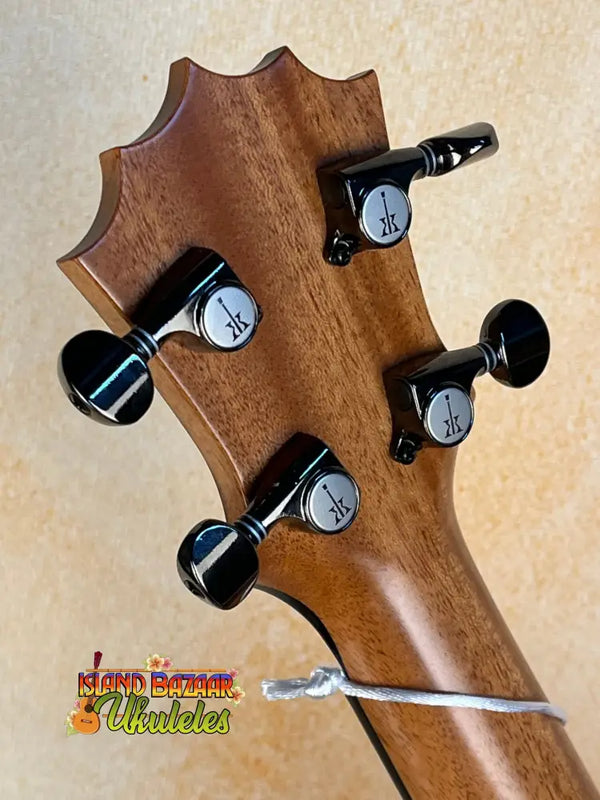 Guitar headstock of KoAloha Royal Pikake Concert KCM-00RP with black tuning pegs and broken string