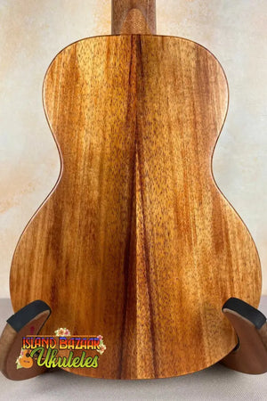 Acoustic guitar with koa wood back panel on stand, showcasing KoAloha Royal Pikake Concert