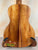 Acoustic guitar with koa wood back panel on stand, showcasing KoAloha Royal Pikake Concert