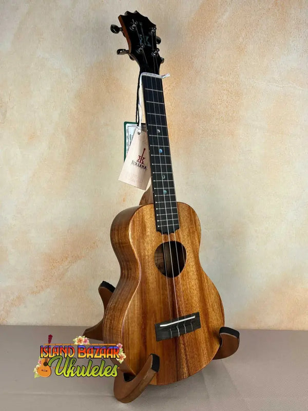 Wooden KoAloha Royal Pikake Concert Ukulele with dark fretboard on display stand