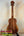 Wooden Koaloha Royal Pikake Tenor Ukulele with natural grain on a black display stand