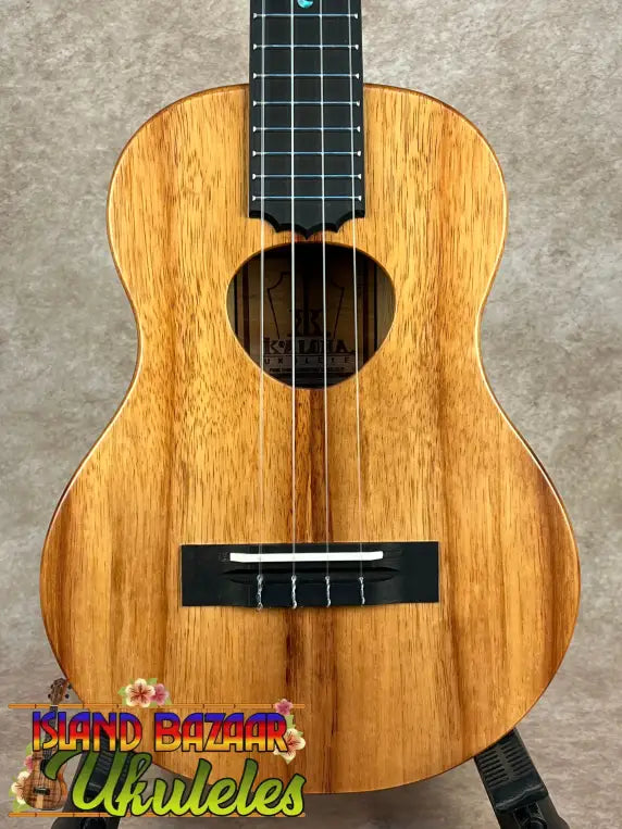 Light brown wooden Koaloha Royal Pikake Tenor ukulele with black fretboard and bridge