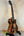 Electric-acoustic Luna Vista Deer Tenor Ukulele with decorative wood patterns on stand