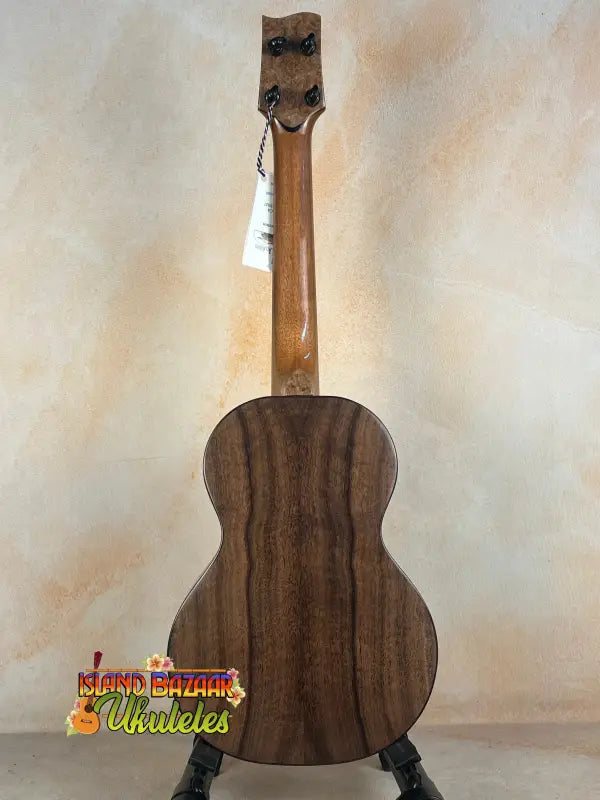 Wooden Nebula Tenor Ukulele on a black stand showcasing Western Red Cedar and Claro Walnut craftsmanship