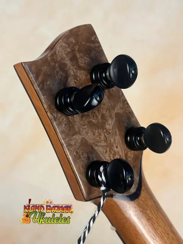 Guitar headstock with black tuning pegs on brown wood, showcasing Nebula Tenor Ukulele design