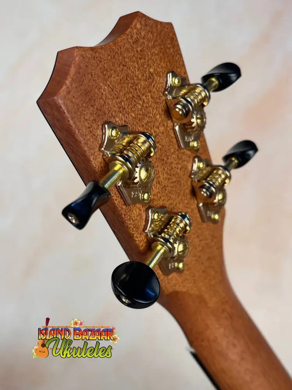 Guitar headstock of Kanile’a Honus Tenor Ukulele with gold tuning pegs and black keys