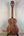 Wooden acoustic guitar with a brown finish on a stand beside Kamaka HF-3I Slothead Tenor