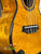 Golden-hued acoustic bass guitar showcasing quilted wood grain for Ohana CK-150SMP