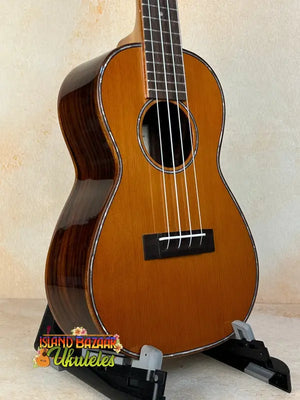Ohana CK-50G Solid Cedar & Rosewood Concert Ukulele on black stand with four strings