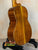 Wooden acoustic guitar with rich brown finish on stand, Ohana TK-350G Tenor Ukulele