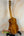 Wooden acoustic guitar on a black stand showcasing Ohana TK-350G Tenor Ukulele