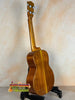 Wooden acoustic guitar on a black stand showcasing Ohana TK-350G Tenor Ukulele