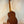 Wooden acoustic guitar on a black stand showcasing Ohana TK-35G Solid Mahogany Tenor Ukulele