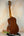 Wooden acoustic guitar on a black stand showcasing Ohana TK-35G Solid Mahogany Tenor Ukulele