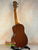 Wooden acoustic guitar on a black stand showcasing Ohana TK-35G Solid Mahogany Tenor Ukulele