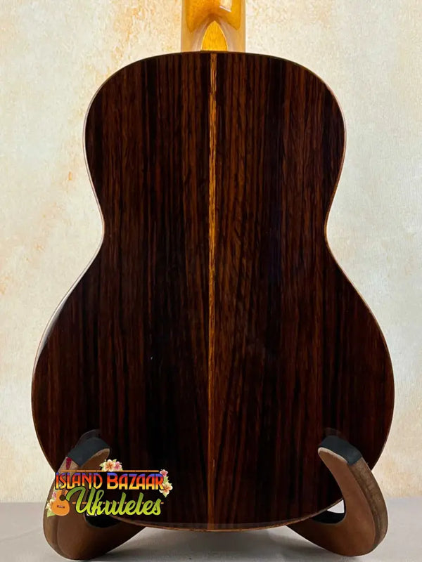 Dark rosewood back panel of Ohana TK-50G Solid Cedar Tenor Ukulele on wooden stand