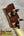 PCH Wickered Oregon Myrtle ukulele headstock with dark reddish-brown wood and gold tuning pegs