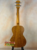 Wooden acoustic guitar with natural finish on stand, ideal for Tenor Mango Ukulele Beginners