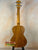 Wooden acoustic guitar with natural finish on stand, ideal for Tenor Mango Ukulele Beginners