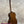 A polished mahogany vintage martin custom baritone ukulele with white tuning pegs standing upright on a black stand