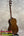 A polished mahogany vintage martin custom baritone ukulele with white tuning pegs standing upright on a black stand