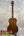 A polished mahogany vintage martin custom baritone ukulele with glossy finish and white tuning pegs on a stand